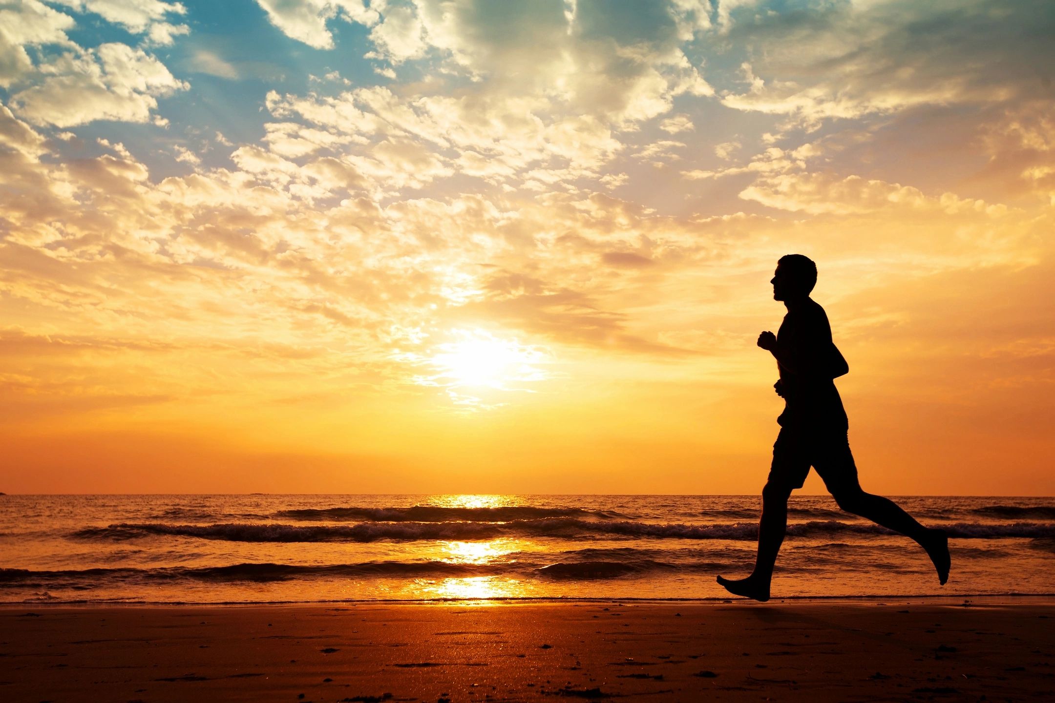 A man jogging on the beach whose wellness provider uses full charge bookkeeping.
